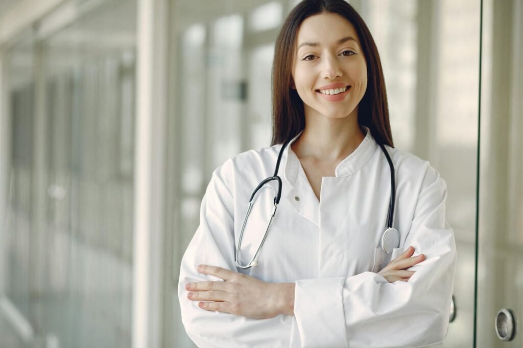 Medical student in white coat holding a stethoscope while studying for NEET
