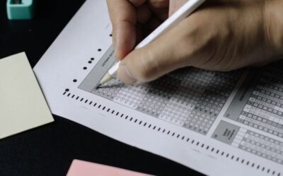 Student reviewing NEET OMR answer sheet on laptop with pen